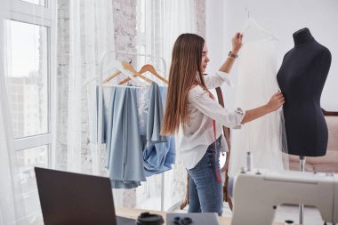 Boyutunu ayarlar. Kadın moda tasarımcısı atölyedeki yeni kıyafetler üzerinde çalışıyor..