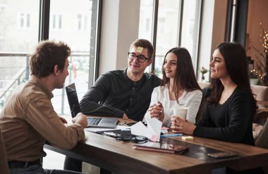 Gözlüklü adamın alnında kedi kelimesi olan bir etiket. Ofis odasında eğleniyorum. Dost canlısı iş arkadaşları ara verdiklerinde etrafta oynuyorlar..
