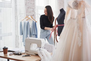 Sürecin içinde gülümsüyordu. Kadın moda tasarımcısı atölyedeki yeni kıyafetler üzerinde çalışıyor..