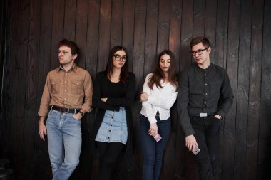 Çok uzun zamandır bekliyorum. Gençlik siyah ahşap duvarın önünde duruyor. Bir grup arkadaş birlikte vakit geçiriyorlar..