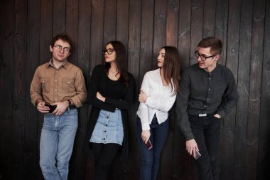 Sol taraftaki adama bakıyorum. Gençlik siyah ahşap duvarın önünde duruyor. Bir grup arkadaş birlikte vakit geçiriyorlar..