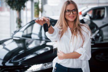 Hepsi paran için. Tamirhanedeki genç müdür mükemmel cilalanmış siyah arabaya karşı duruyor..