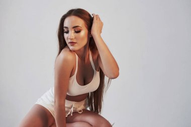 Manken saçına dokunuyor. Stüdyoda beyaz arka planda baştan çıkarıcı esmer portresi..