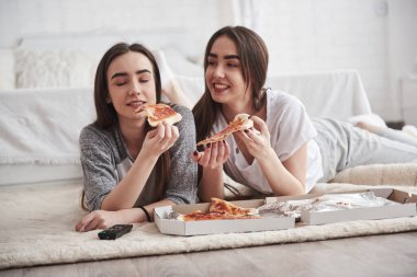 Taze ve sıcak yemeğin tadını çıkarıyorum. Gündüz vakti güzel yatak odasının zemininde yatarken TV izlerken pizza yiyen rahibeler..
