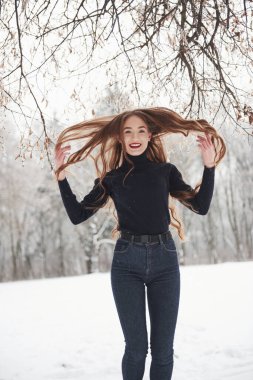 O, saçına aşık. Uzun saçlı ve siyah bluzlu güzel kız kış ormanında..