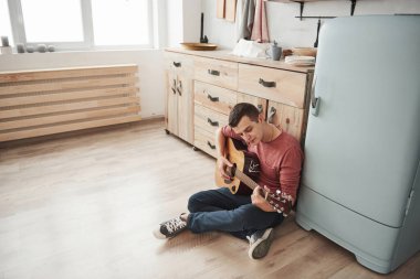 Yeni bir şarkı öğreniyorum. Müzisyen hafta sonu evde, mutfakta akustik gitar çalar..
