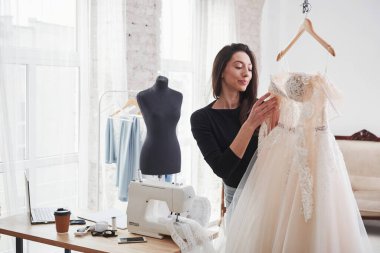 Elbiseye bakıyorum. Kadın moda tasarımcısı atölyedeki yeni kıyafetler üzerinde çalışıyor..