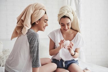 Şaka yapıyordum. Yüzünde beyaz maske kullanarak cilt bakımı kavramı. İki kız kardeş hafta sonunu yatak odasında geçirir..