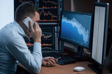 Odada yalnızdım. Ofiste çalışan adamın indeks grafiklerinde birden fazla bilgisayar ekranı var..