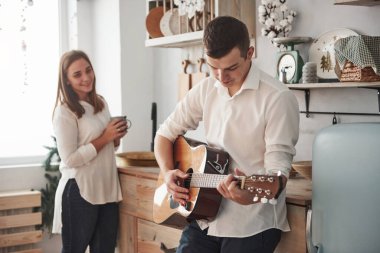 Kız gülümsüyor. Genç gitarist mutfakta kız arkadaşına aşk şarkısı çalıyor..