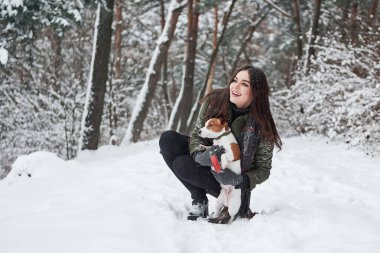 Nereye gitmemiz gerekiyor? Kış parkında köpeğiyle yürürken gülümseyen esmer..