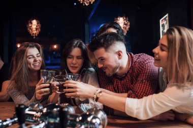 Mutluluk için. Gece kulübünde gülümseyen ve kadeh kaldıran bir grup genç arkadaş..