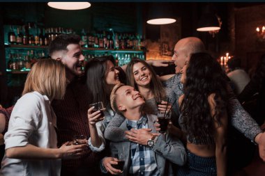 Kadın, önünde duran adama sarılıyor. Güzel gençler gece kulübünde alkolle parti yaparlar..