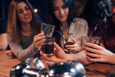 Viski iç. Gece kulübünde gülümseyen ve kadeh kaldıran bir grup genç arkadaş..