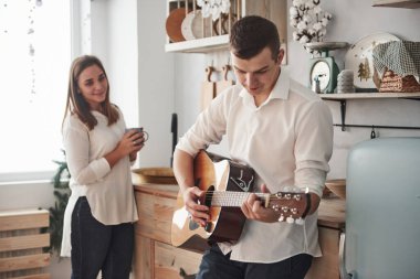 Genç gitarist mutfakta kız arkadaşına aşk şarkısı çalıyor..