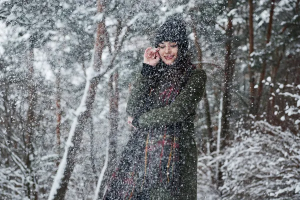 それは美しい雪です 暖かい服の陽気な若い女の子は昼間に冬の森の中を散歩しています — ストック写真