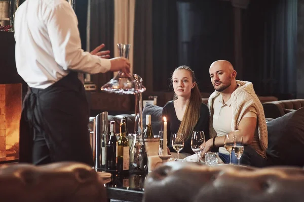 侍者解释为什么他们的酒比别人的好 女孩和她的男朋友在漂亮的餐厅度过了一个愉快的夜晚 — 图库照片