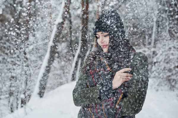 寒いわね 暖かい服の陽気な若い女の子は昼間に冬の森の中を散歩しています — ストック写真