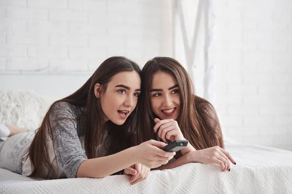 Aumenta Volume Duas Gêmeas Deitadas Cama Branca Durante Dia Assistindo — Fotografia de Stock