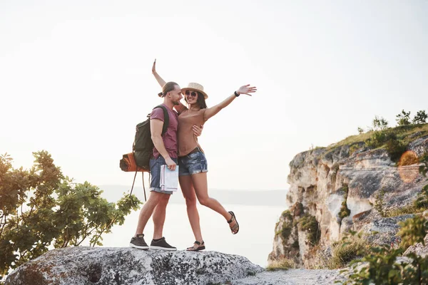バックパック付きの2人の観光客の男性と女性は クレイグの上に立って日の出を楽しんでいます 山や海岸を旅し 自由とアクティブなライフスタイルのコンセプト — ストック写真