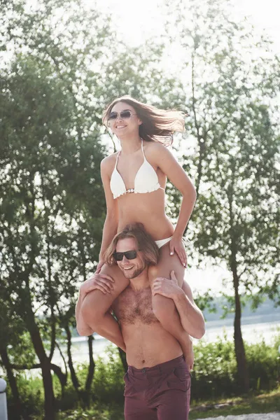 幸せな若い男がビーチの肩に妻を着て — ストック写真