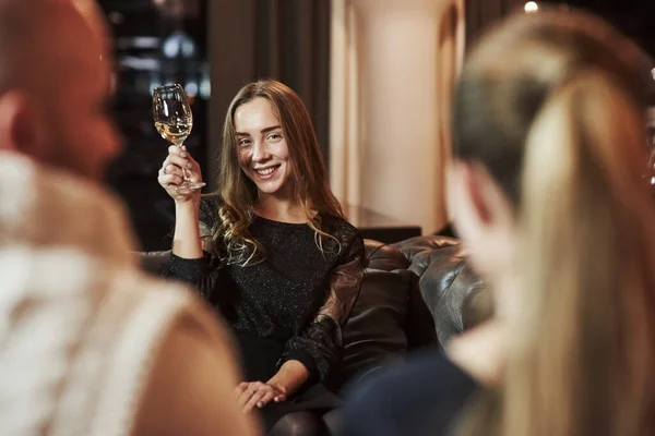 年轻美丽的金发姑娘的画像 她与饭店里的朋友在一起 手里拿着装有香槟的杯子 — 图库照片