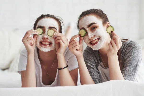 ホーム美容室 新鮮なキュウリリングと顔に白いマスクを使用してスキンケアの概念 2人の女性姉妹持っています週末にベッドルーム — ストック写真