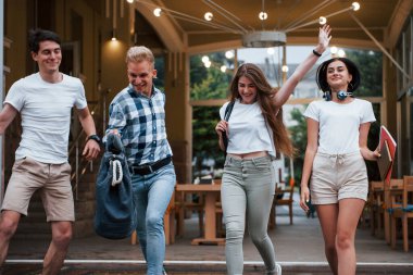 Ön manzara. Gündelik giysiler içinde dört genç öğrenci yağmurlu bir günde buluşuyor..