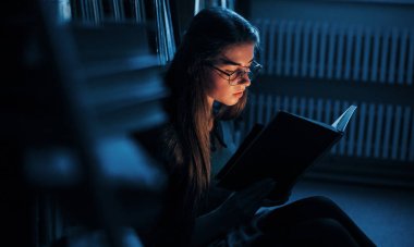 Her geçen gün daha da akıllanıyor. Kütüphanede kitaplarla dolu bir kız öğrenci var. Eğitim kavramı.