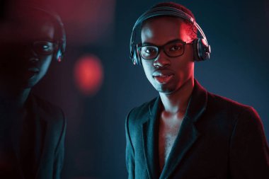 Kulaklıkla müzik dinlemeyi seviyorum. Gözlüklü. Fütürist neon ışıkları. Stüdyodaki Afrikalı Amerikalı genç adam..