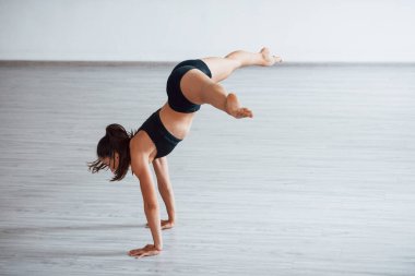 Amuda kalkmak. Siyah elbiseli, zayıf vücutlu genç, sportif bir kadın. Sağlık merkezinde egzersiz yapıyor..