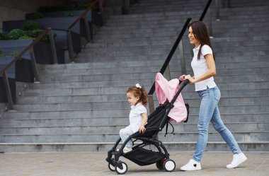 Pembe bebek arabalı güzel anne ve küçük kızı şehirde yürüyüşe çıktılar..