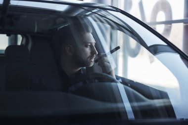 Saf zarafet. Lüks siyah arabasında oturan sakallı genç işadamının ön görüntüsü..