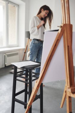 Binanın planı siyah sandalyede yatıyor. Beyaz duvarları ve pencereden gelen gün ışığıyla odada genç bir esmer..