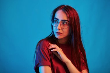 Mavi arka planda bir kadın. Stüdyo içeride neon ışıkla çekiliyor. Güzel bir genç kızın portresi.