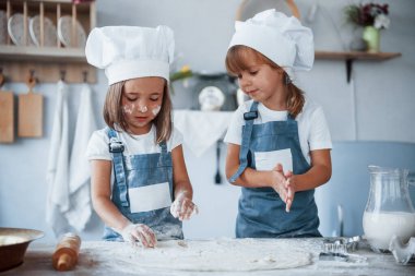 Yemek pişirmeye odaklan. Beyaz şef üniformalı aile çocukları mutfakta yemek hazırlıyorlar..