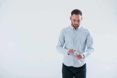 Mola zamanı. Elinde su olan bir şişe. Resmi kıyafetli adam stüdyoda beyaz arka plana karşı duruyor..