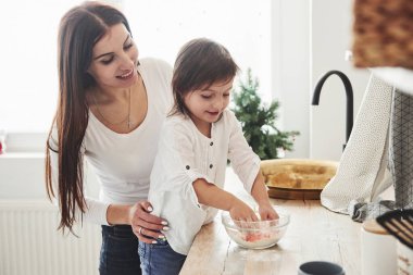 Yemek yapmayı öğren. Mutlu kız ve anne birlikte fırın ürünleri hazırlıyorlar. Mutfakta küçük bir yardımcı..
