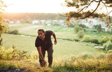 O tepeyi fethetmek. Kırsal alan. Kaslı vücutlu yakışıklı adam gündüz vakti ormanda olur..