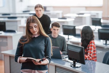 Kitap okuyorum. Modern ofiste çalışan günlük kıyafetli bir grup genç..