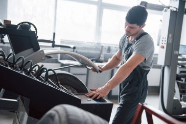 İşlem tamamlandı. Genç adam gündüz atölyesinde tekerlek diskleriyle çalışıyor..
