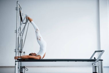 Etkili makine. Sağlıklı merkezde zayıf vücutlu, kendine güvenen genç bir kadın özel ekipman kullanarak egzersiz yapıyor..