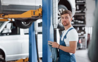 Elinde bez parçasıyla. Mavi üniformalı işçi otomobil salonunda çalışıyor..