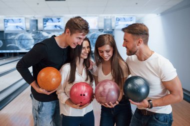 Birbirinize sarılın. Genç neşeli arkadaşlar hafta sonları bowling kulübünde eğleniyorlar..