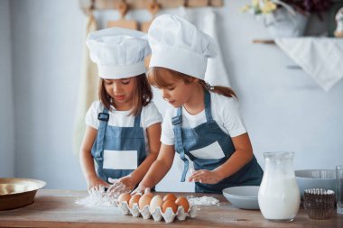 Beyaz şef üniformalı aile çocukları mutfakta yemek hazırlıyorlar..
