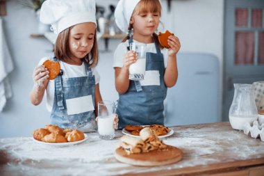 Sütlü bardak. Beyaz şef üniformalı aile çocukları mutfakta yemek hazırlıyorlar..