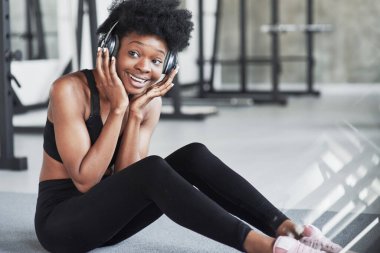 Yüz ifadesi. Kıvırcık saçlı ve spor elbiseli Afrikalı Amerikalı kadın spor salonunda spor yapıyor..