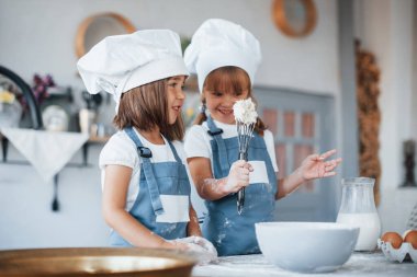 Beyaz şef üniformalı aile çocukları mutfakta yemek hazırlıyorlar..