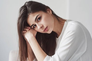 Muhteşem bir kadının güzel portresi. Beyaz duvarları ve pencereden gelen gün ışığıyla odada genç bir esmer..