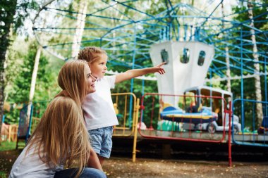 Birbirimizi sevmek. Neşeli küçük kız. Annesi eğlence parkında iyi vakit geçiriyor..